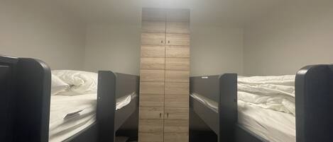 A bunk room with two beds and a wooden wardrobe.