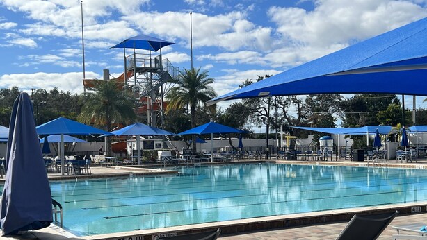 A swimming pool with blue umbrellas, lounge chairs, and a lifeguard tower in the background. - Cottage in Sun Outdoors Sarasota (Sarasota)