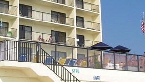 Un hotel de varios pisos con balcones, asientos al aire libre y una bandera estadounidense.