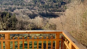 A wooden deck overlooking a forested valley with a mountain in the background.