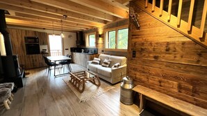 A cozy cabin interior with a wooden interior, a dining area, a sofa, and a fireplace.