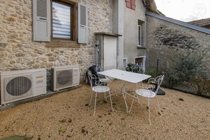 Relax in a charming outdoor space with a table and chairs, surrounded by lush greenery.