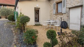 A stone house with a small garden, a white table and chairs, and a black bag. - Deja Viuz - Chindrieux (CHINDRIEUX)
