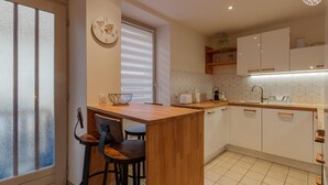 A modern kitchen with a wooden island, white cabinets, and a tiled backsplash. - Deja Viuz - Chindrieux (CHINDRIEUX)