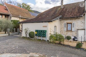 Traditional building with a sloped roof, green mailboxes, and a neatly trimmed bush.