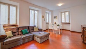 A living room with a sectional sofa, a dining table with chairs, and large windows. - La Casa di Maddalena Stresa Centre: 2 Bed, 2 Bath, Balconies (Stresa)