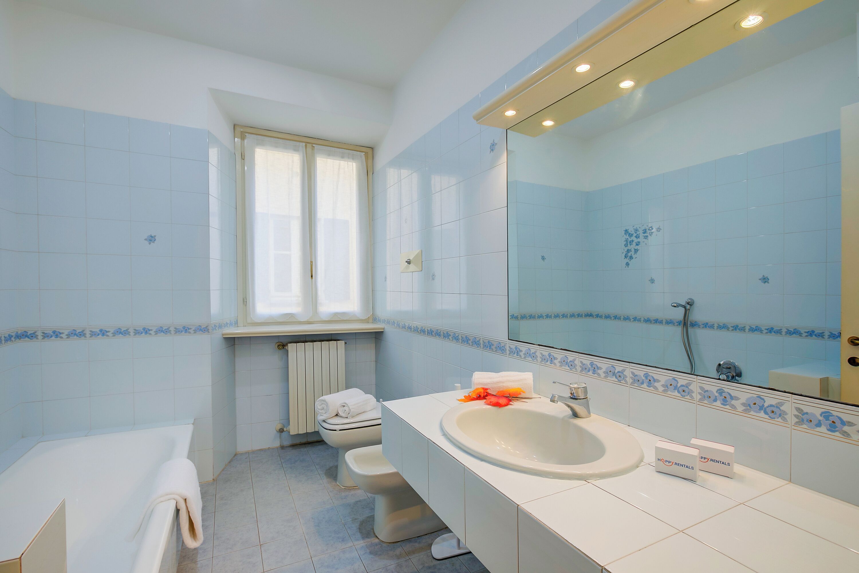Ein Badezimmer mit Badewanne, Toilette, Waschbecken und einem großen Spiegel.