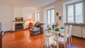 A spacious living room with a fireplace, a dining area with a table set for four, and large windows providing natural light. - La Casa di Maddalena Stresa Centre: 2 Bed, 2 Bath, Balconies (Stresa)
