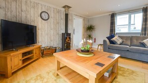 Una sala de estar con televisión, muebles de madera, chimenea y sofá.