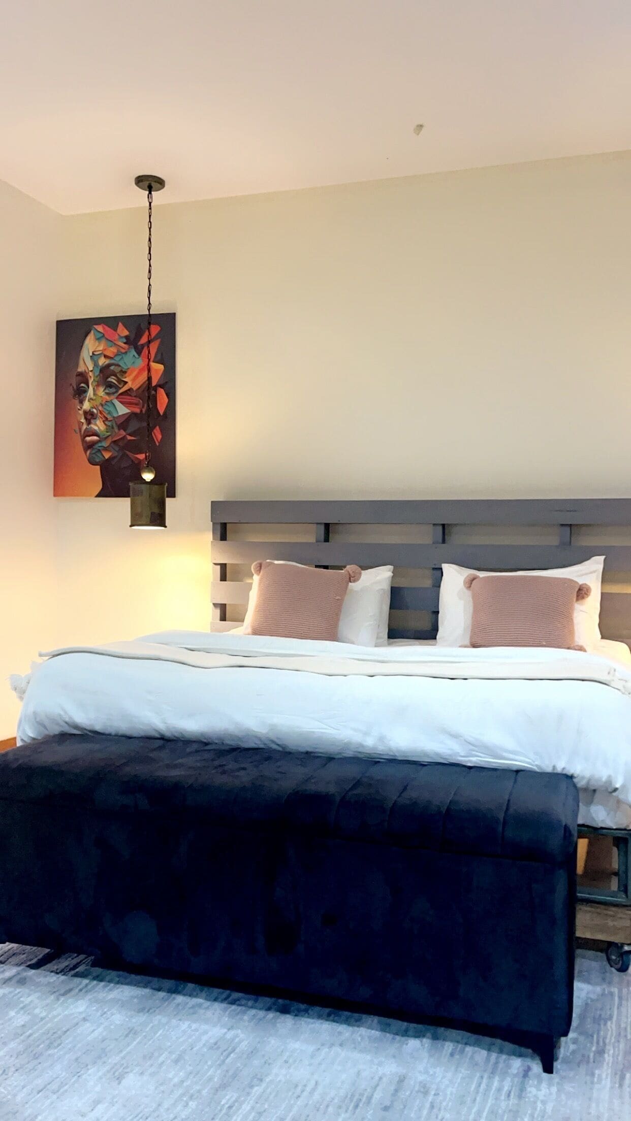 A modern bedroom with a bed, a bench, and a painting on the wall.