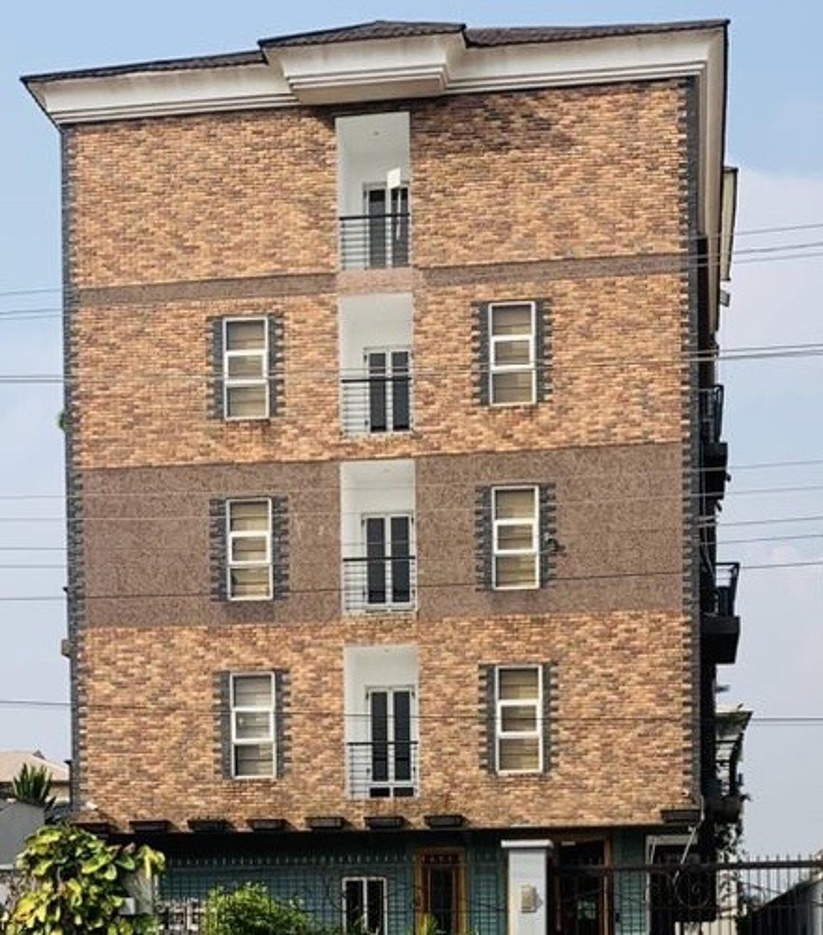 Ein mehrstöckiges Backsteingebäude mit einer symmetrischen Fassade, zahlreichen Fenstern und einem zentralen Eingang.