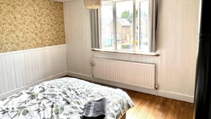 Quarto com cama, janela, radiador e luminária pendente.
