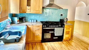 Uma cozinha compacta com armários de madeira, micro-ondas, fogão a gás e pia.