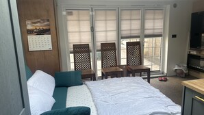 A bedroom with a bed, a wooden desk, a TV, a calendar, and a sliding glass door leading to an outdoor area. - Stunning 1-bed Studio in London (London)