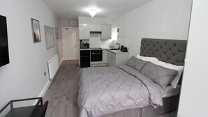 Ein kleines Schlafzimmer mit einem Bett, einem Einbauschrank und einer Küchenzeile.
