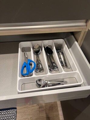 Eine Schublade mit Fächern, die verschiedene Utensilien und ein blaues Messer enthalten.