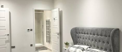 A modern bedroom with a large bed, a bedside table, and a walk-in closet.
