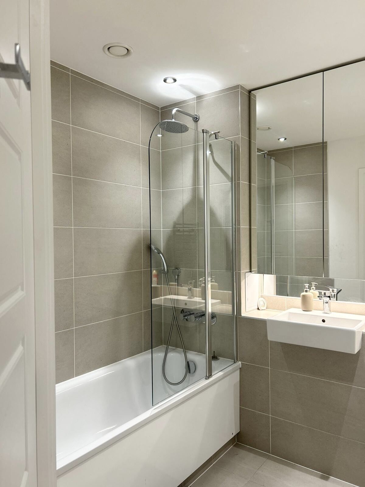 Un bagno moderno con doccia a vetro, vasca da bagno bianca e lavabo con specchio sopra.