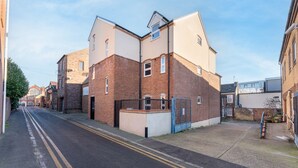 Een rustige straat met woonhuizen, een combinatie van bakstenen en moderne gevels, met een duidelijke weg en zonder zichtbare voorzieningen of kenmerken.