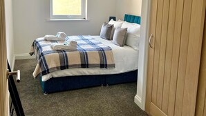 Een slaapkamer met een bed, een raam, een kledingkast en een hanglamp.