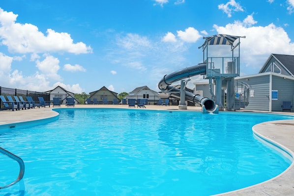 A swimming pool with a water slide and a lifeguard tower.