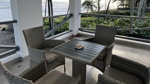 En balkon med fletmøbler og havudsigt.