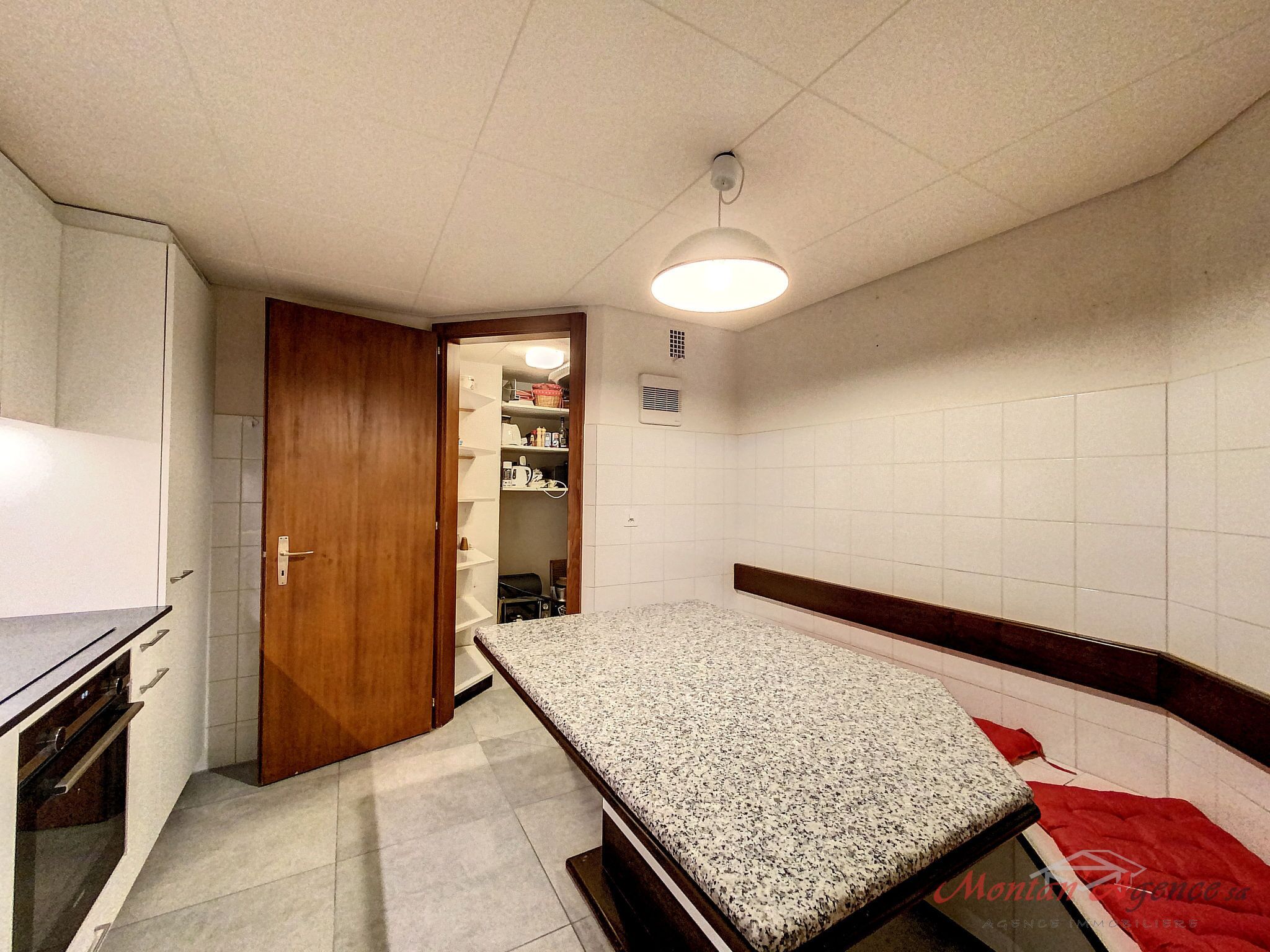 A small, compact room with a kitchenette, a bed, and a wardrobe.