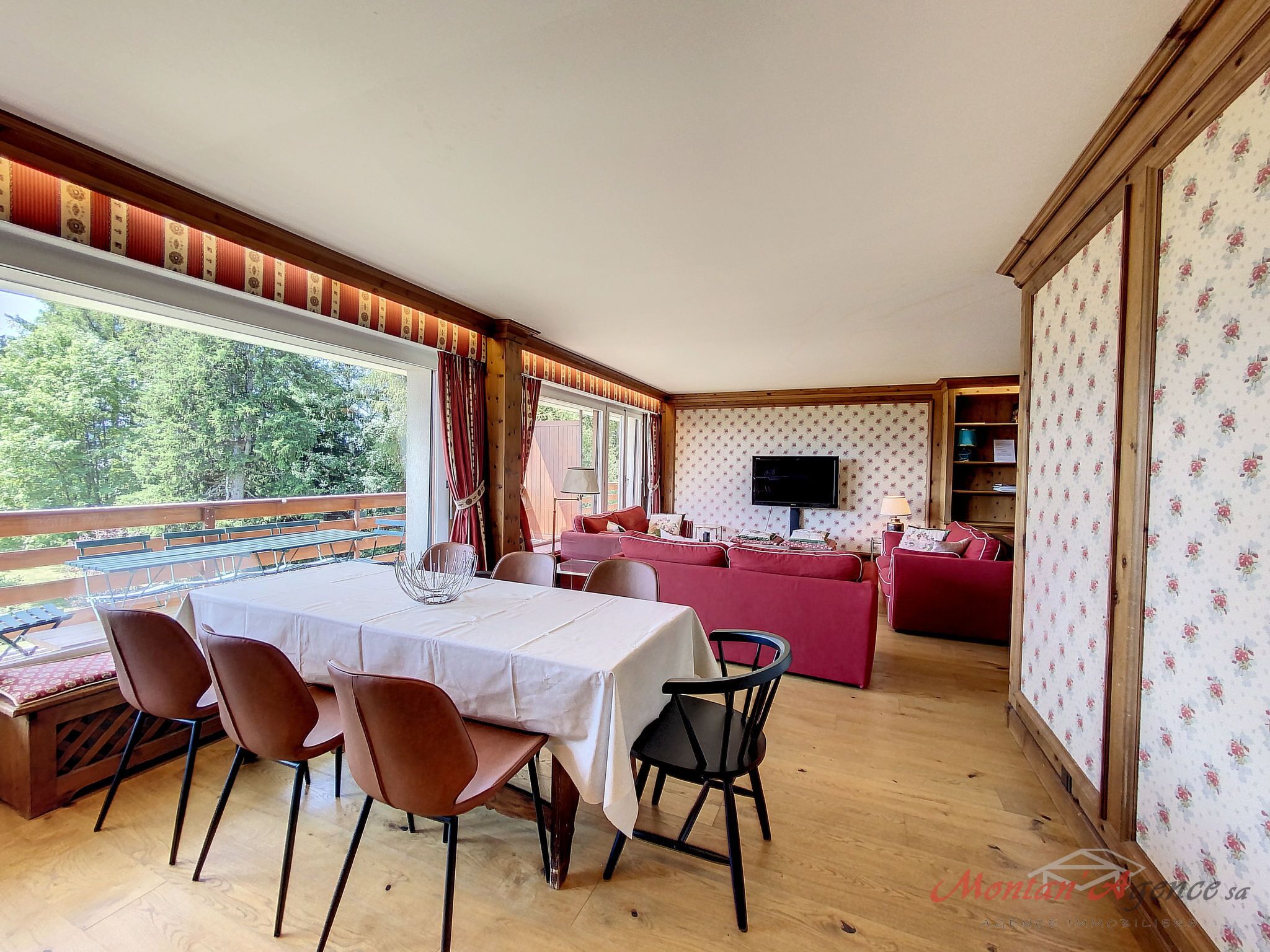Un coin repas avec une table et des chaises, un ensemble de canapés et un téléviseur.