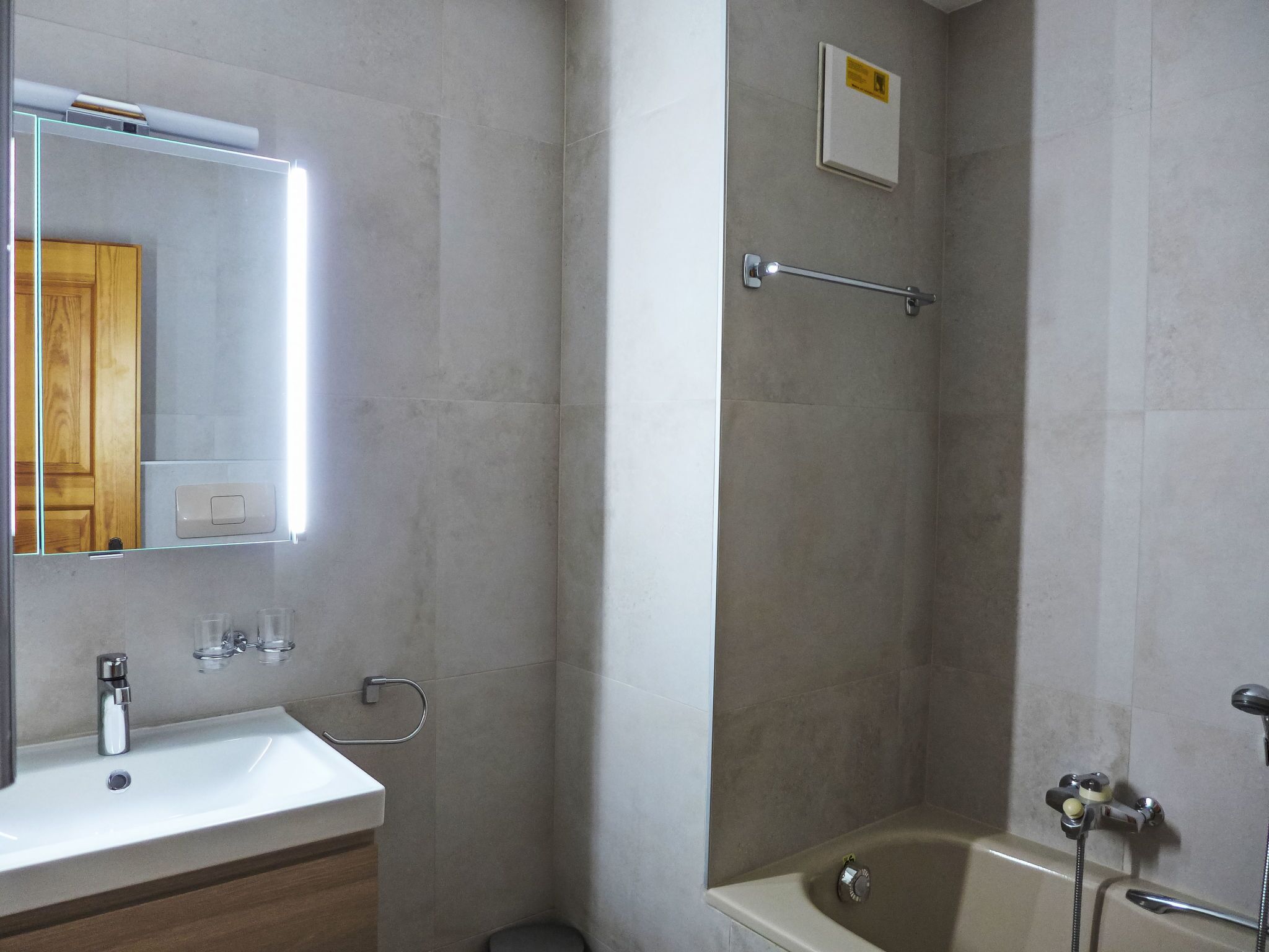A bathroom with a sink, mirror, towel rack, and a shower with a handheld showerhead.