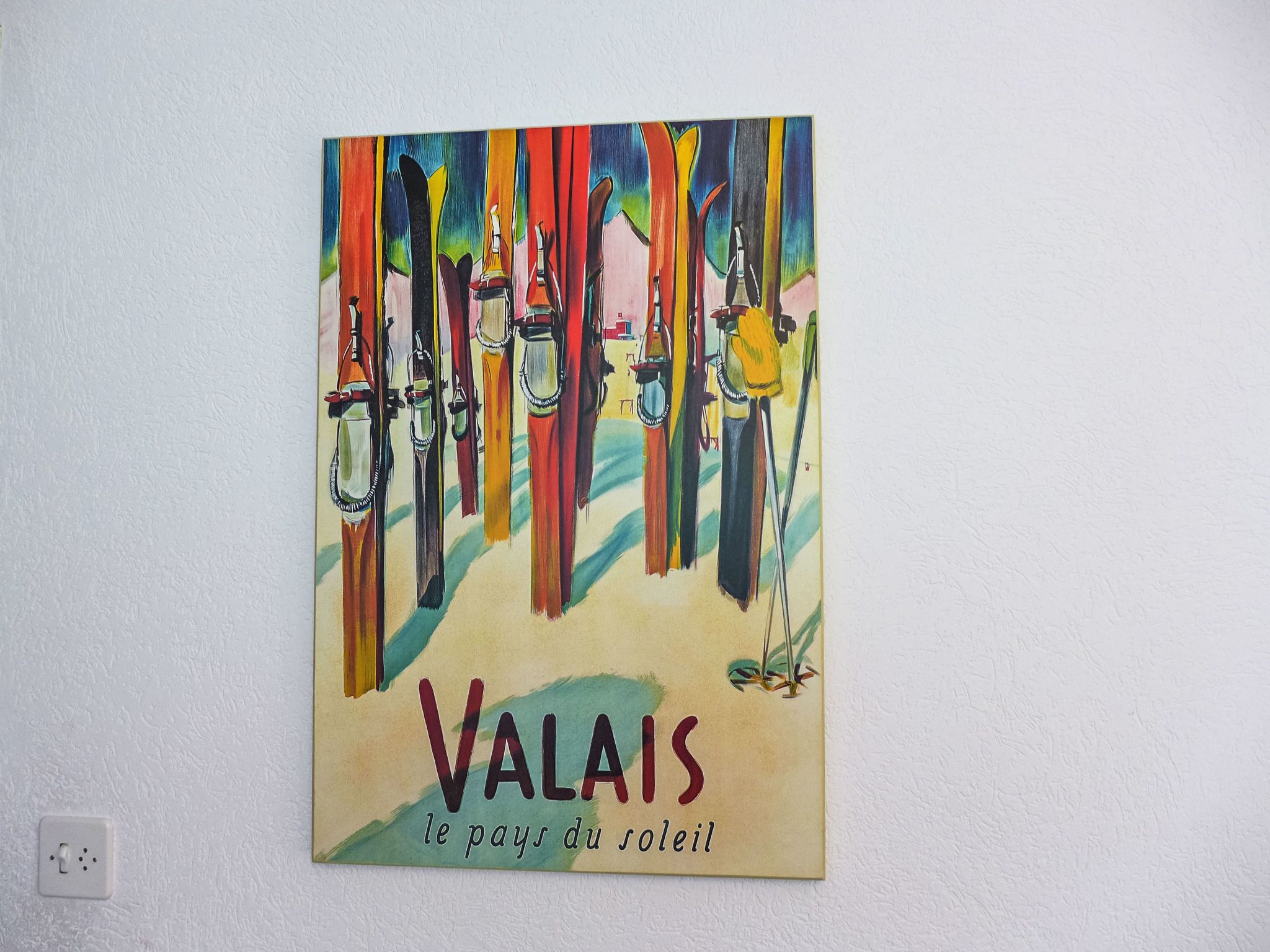 Ein farbenfrohes Gemälde mit dem Titel „VALAIS le pays du soleil“, das Ski und einen Skifahrer zeigt.