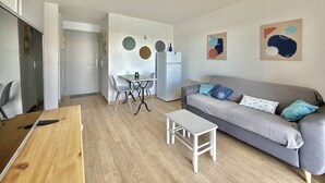 Un appartement moderne comprenant un coin repas, un canapé et des œuvres d’art abstraites accrochées au mur.