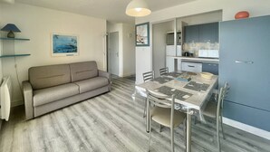 A compact living space with a sofa, dining table, chairs, a kitchen area, and a ceiling light. - CAP D'AGDE - L'Ile des pêcheurs / Réf 0216 (CAP D'AGDE)