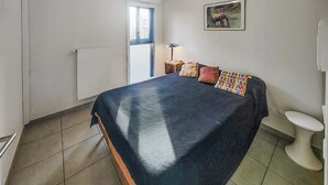 A bedroom with a bed, a window, a radiator, a lamp, and a painting on the wall. - Pet friendly home in Agde with WiFi (Agde)