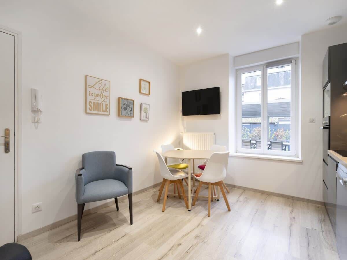 Un espace de vie compact comprenant un coin repas, un téléviseur fixé au mur et une fenêtre donnant sur l’extérieur.