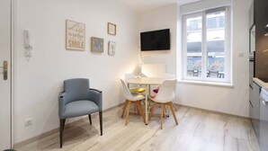 Un espacio habitable compacto con zona de comedor, televisor montado en la pared y ventana con vistas al exterior.