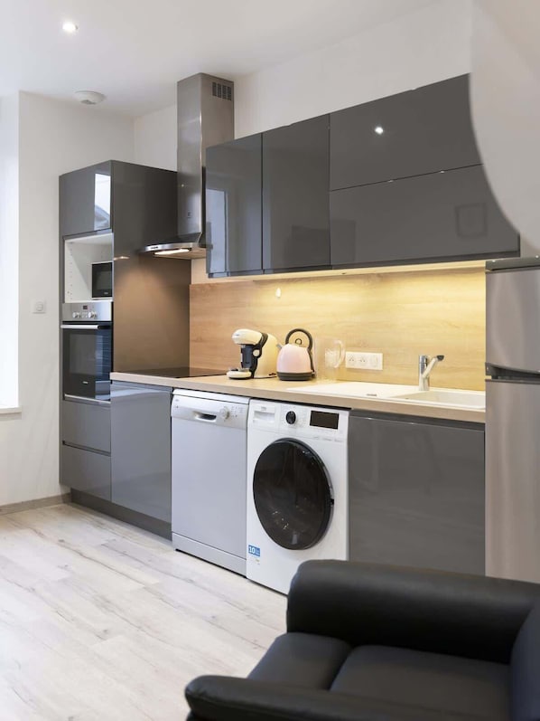 A modern kitchen with a built-in washing machine, a microwave, and a sink.