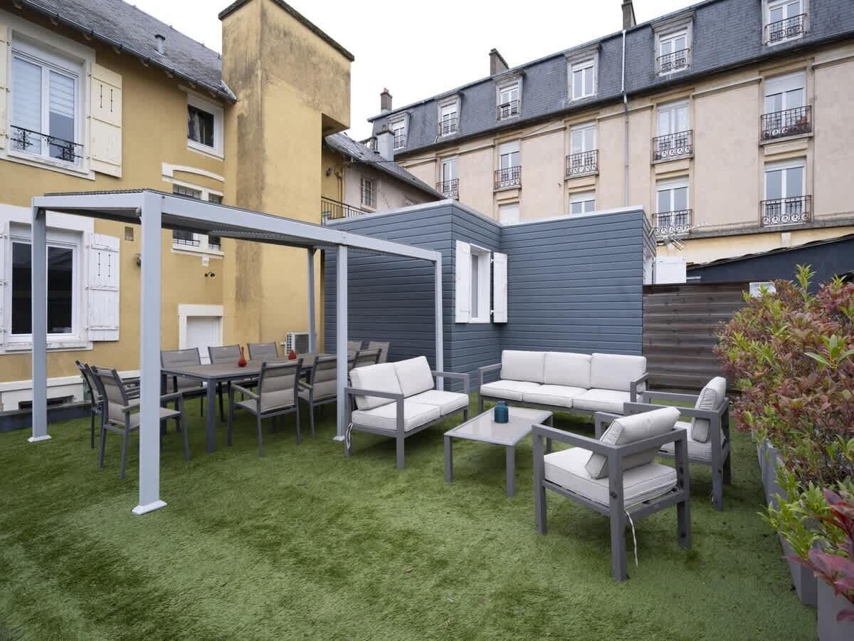 Une terrasse avec des meubles d’extérieur, une pergola et une pelouse verdoyante.