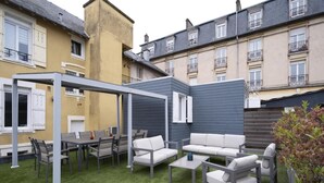 Un patio con mobiliario exterior, una pérgola y un césped verde.