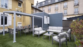 Une terrasse avec des meubles d’extérieur, une pergola et une pelouse verdoyante.