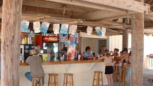 A wooden bar area with stools, a Coca-Cola refrigerator, and Corona beer boxes. - Sandpiper Cove unit 9138 with beach service (Destin)