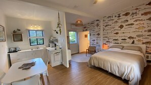Un dormitorio con cama, escritorio con silla, kitchenette y decoración temática de peces.