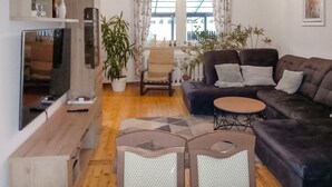 A living room with a sofa, a small round table, a TV, and a chair.