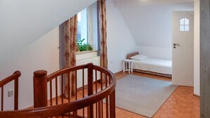 A staircase with a wooden handrail leading to a room with a white sofa and a small window with curtains.