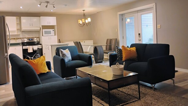 A modern living room with two sofas, a coffee table, and a dining area with chairs and a glass table. - The Beautiful Nubia - 5 Mins Drive to the Calypso Waterpark.  (Limoges)