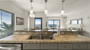 A modern kitchen with granite countertops, stainless steel sinks, and pendant lighting. - Origin 635: Stunning Gulf Views | High-Demand Condo | Free Activities! (Panama City Beach)