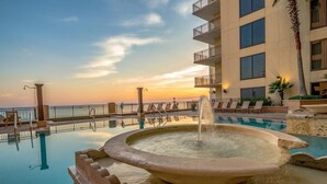 A pool with a central fountain, surrounded by lounge chairs and a building with balconies. - Origin 635: Stunning Gulf Views | High-Demand Condo | Free Activities! (Panama City Beach)