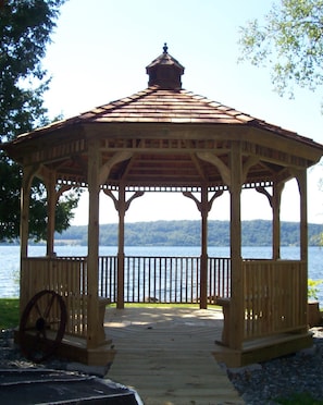 Ein hölzernes Gazebo mit Ziegeldach mit Blick auf einen See.