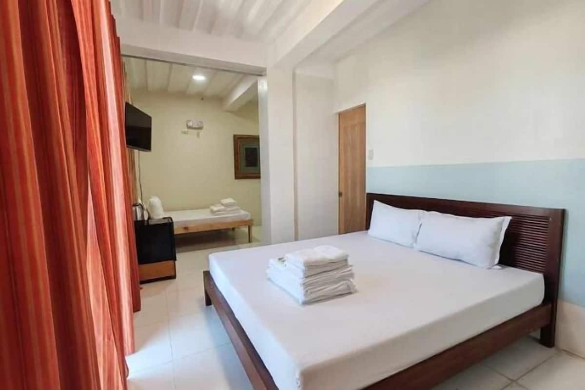 A hotel room with a large bed, a bedside table, a mirror, and a bathroom visible through an open door.