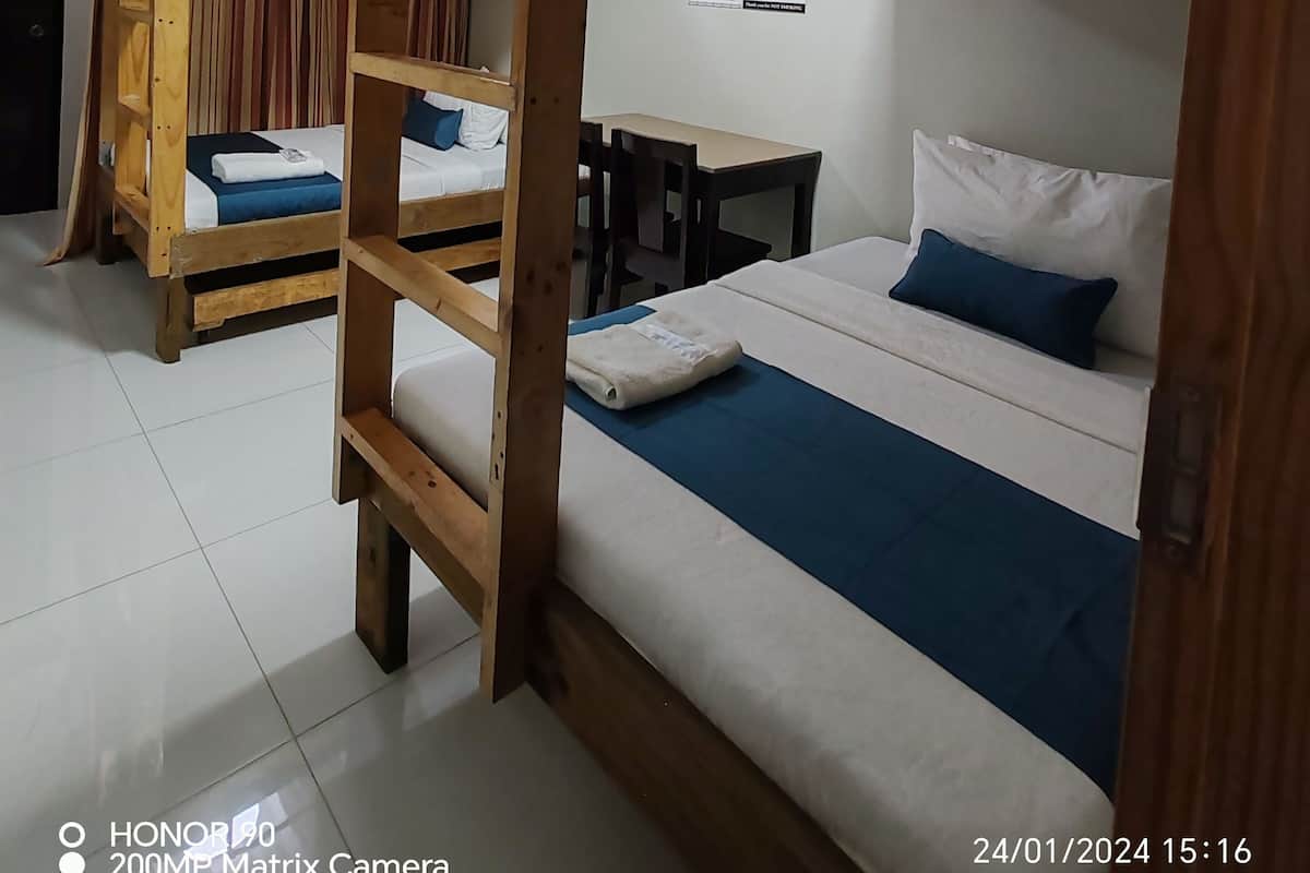 A room with bunk beds, a desk, and a chair.