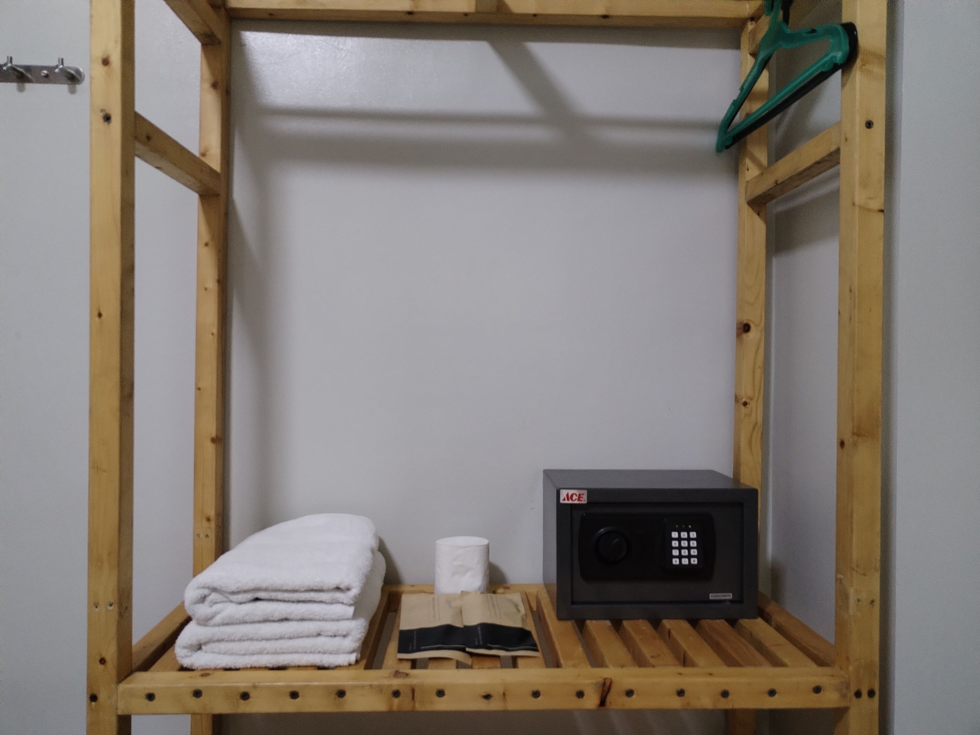 Una estantería de madera con toallas dobladas, un rollo de papel higiénico y una radio negra.